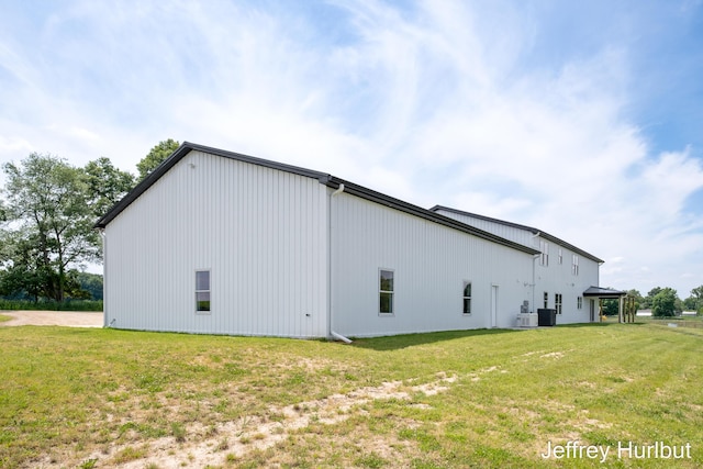 view of side of property with an outbuilding, a yard, and central AC