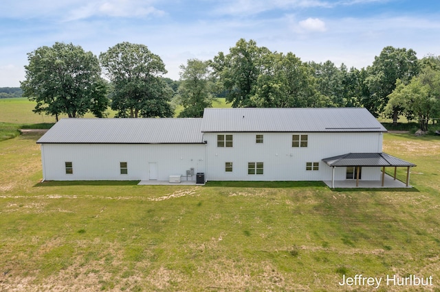 rear view of house featuring metal roof, a lawn, a patio area, and cooling unit