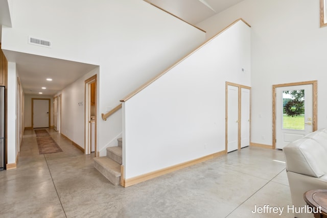 interior space with finished concrete flooring, stairs, a high ceiling, and visible vents