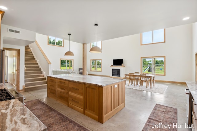 kitchen featuring finished concrete floors, visible vents, open floor plan, and a fireplace