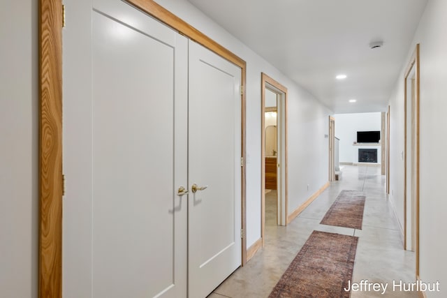 hallway with finished concrete flooring, baseboards, and recessed lighting