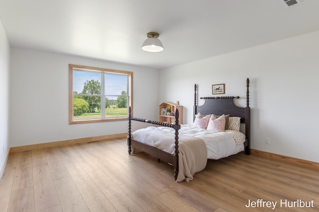 bedroom with light wood-style floors, visible vents, and baseboards