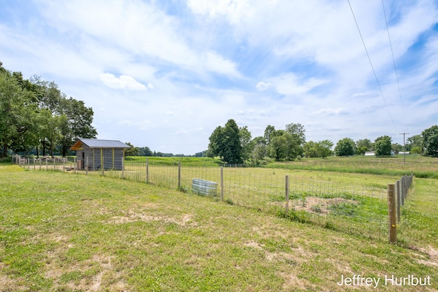 view of yard featuring a rural view, fence, and an outdoor structure