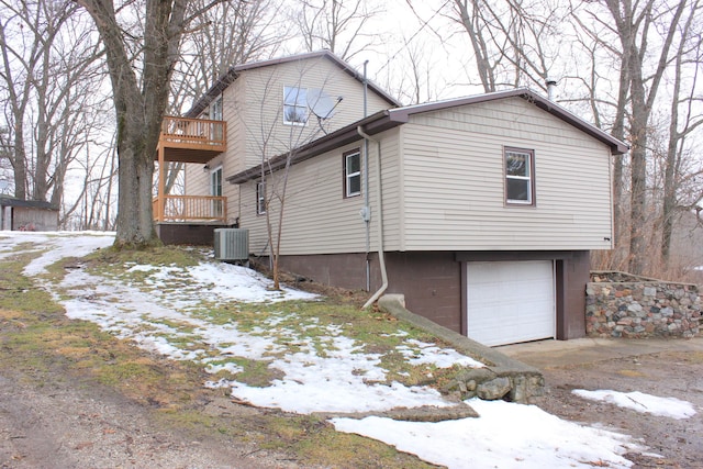 snow covered property with an attached garage and central AC