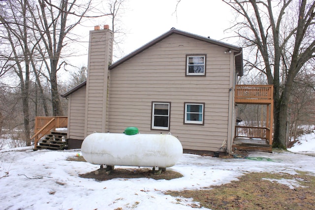 snow covered back of property with a chimney