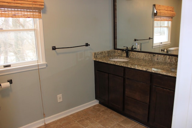 bathroom featuring toilet, tile patterned flooring, vanity, and baseboards