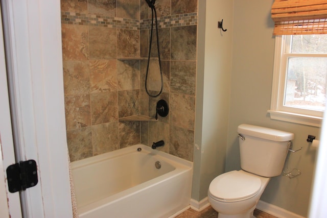 bathroom with shower / tub combination, toilet, and baseboards