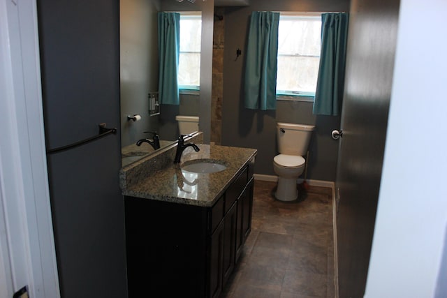 bathroom featuring plenty of natural light, vanity, toilet, and baseboards