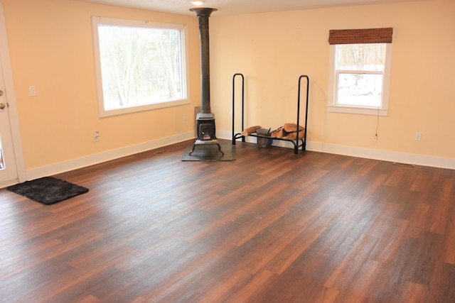 workout area featuring a wood stove, baseboards, and dark wood-type flooring