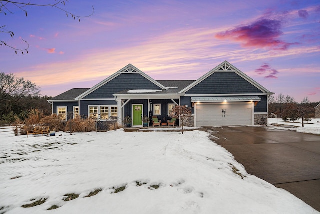 view of front facade with a garage, stone siding, driveway, and a porch