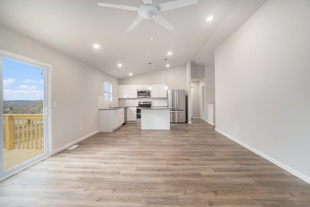 kitchen with light wood-style flooring, stainless steel appliances, white cabinets, open floor plan, and hanging light fixtures