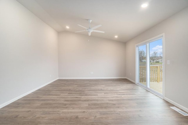 unfurnished room featuring lofted ceiling, visible vents, light wood-style flooring, and baseboards