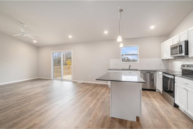 kitchen featuring a center island, decorative light fixtures, dark countertops, appliances with stainless steel finishes, and white cabinetry