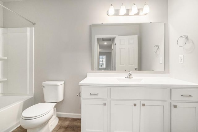 full bath with toilet, wood finished floors, vanity, baseboards, and washtub / shower combination