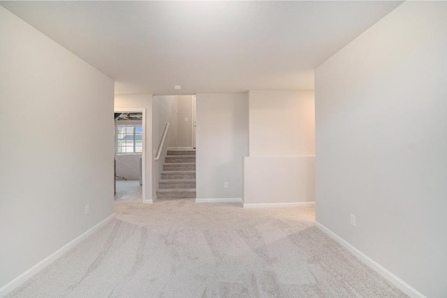 unfurnished room with light carpet, stairway, and baseboards