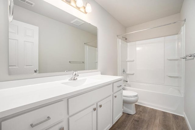 bathroom featuring visible vents, toilet, wood finished floors, vanity, and shower / washtub combination