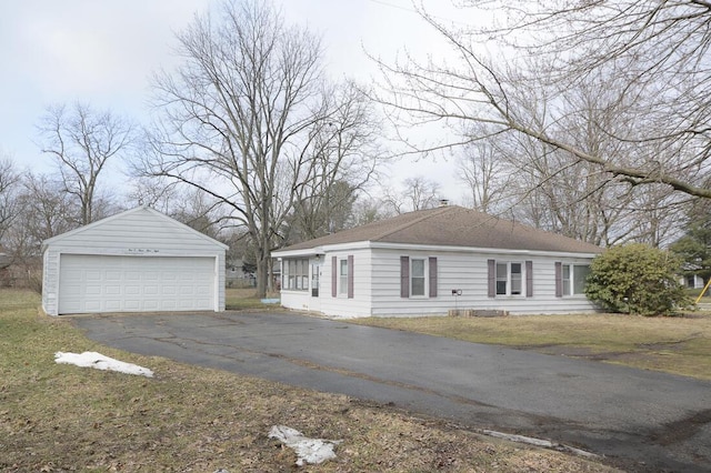 view of front facade featuring a front yard, roof with shingles, a detached garage, and an outbuilding