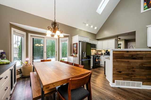 dining space featuring high vaulted ceiling, dark wood-type flooring, a skylight, visible vents, and an inviting chandelier