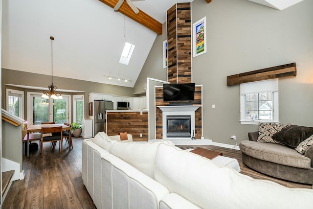 living room with a healthy amount of sunlight, dark wood finished floors, beamed ceiling, and a fireplace