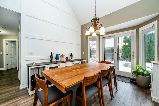 dining room featuring dark wood-style floors, vaulted ceiling, a decorative wall, and an inviting chandelier