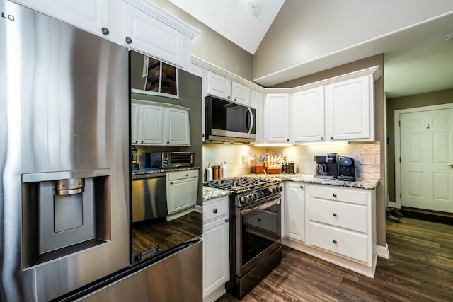 kitchen with white cabinets, lofted ceiling, light stone counters, stainless steel appliances, and backsplash