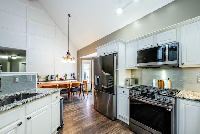 kitchen featuring vaulted ceiling, white cabinetry, stainless steel appliances, and backsplash