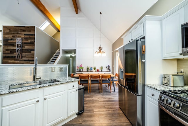 kitchen featuring decorative backsplash, white cabinets, appliances with stainless steel finishes, decorative light fixtures, and a sink