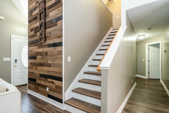 stairs featuring wood walls, wood finished floors, and baseboards