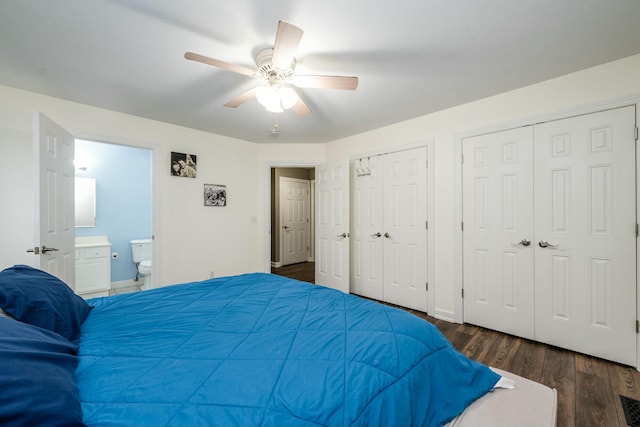 bedroom featuring ceiling fan, dark wood finished floors, two closets, baseboards, and ensuite bath