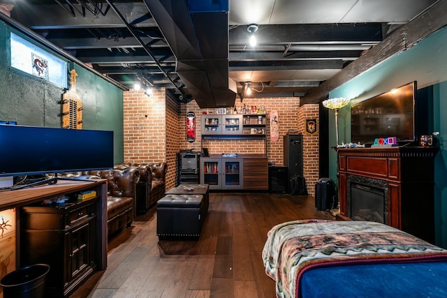 living area featuring brick wall, a fireplace, and hardwood / wood-style floors