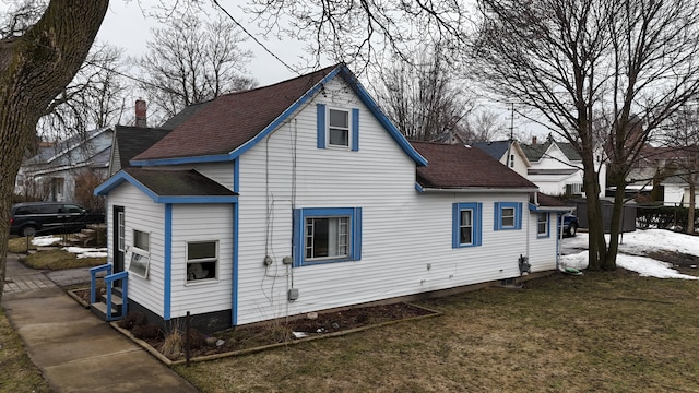 rear view of house with a shingled roof, a chimney, and a yard