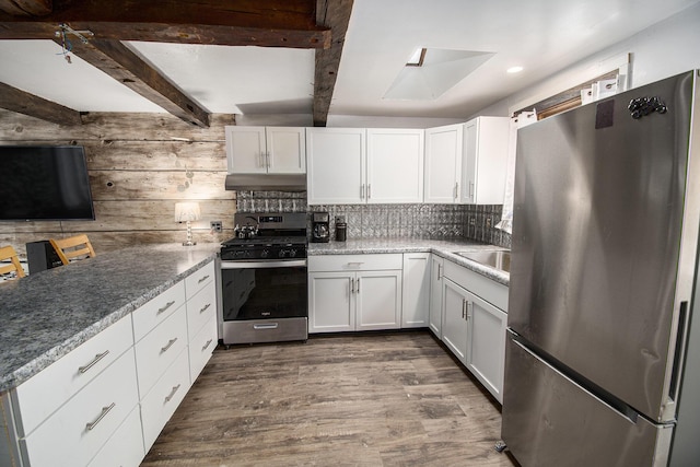 kitchen with dark wood-style floors, appliances with stainless steel finishes, white cabinetry, beamed ceiling, and under cabinet range hood