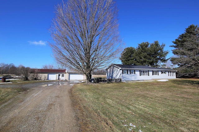 single story home featuring driveway, an outdoor structure, and a front yard