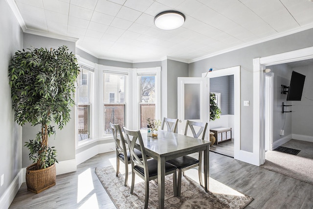 dining room with crown molding, baseboards, and wood finished floors