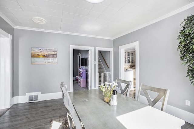 dining room featuring visible vents, crown molding, baseboards, and wood finished floors