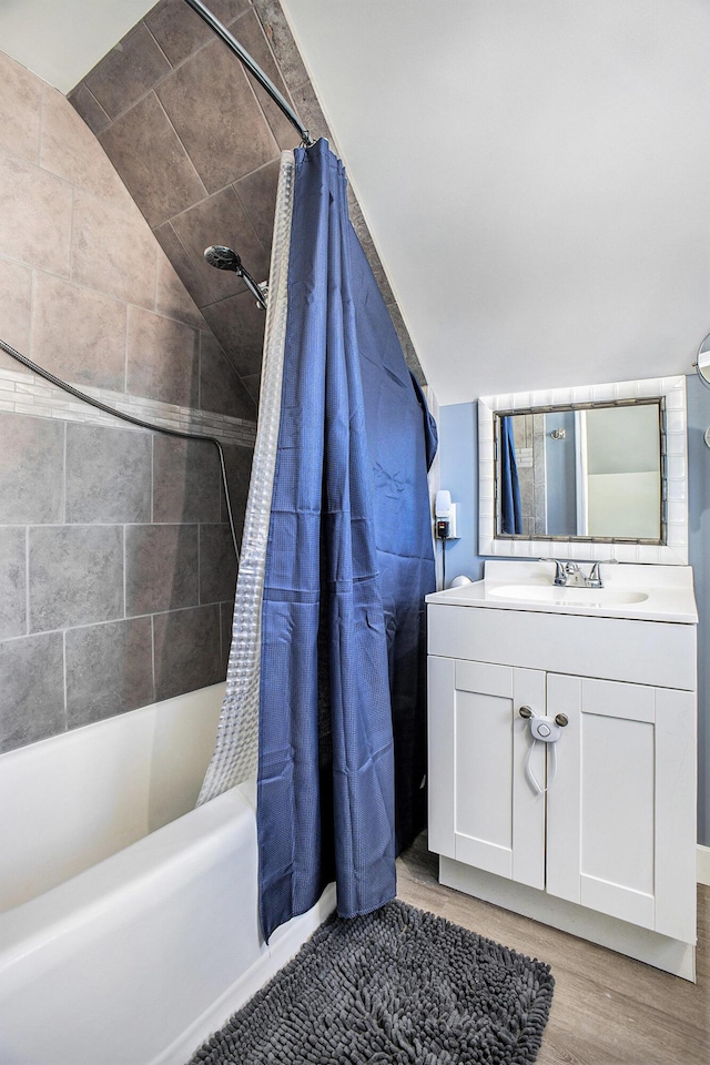 bathroom with lofted ceiling, wood finished floors, shower / bath combination with curtain, and vanity