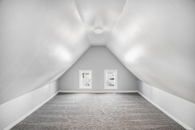 additional living space featuring baseboards, vaulted ceiling, and carpet flooring