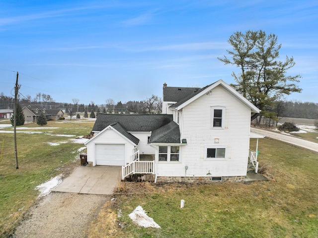 back of house featuring a garage, driveway, a shingled roof, and a lawn