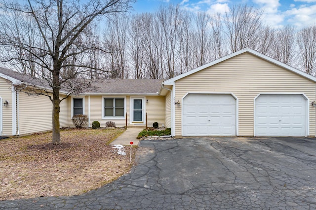 single story home with an attached garage, a shingled roof, and aphalt driveway