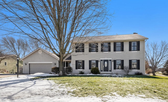 colonial house with an attached garage, driveway, a chimney, and a front lawn