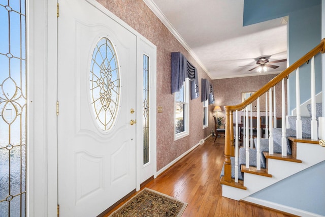 entrance foyer with stairway, ornamental molding, wood finished floors, baseboards, and wallpapered walls