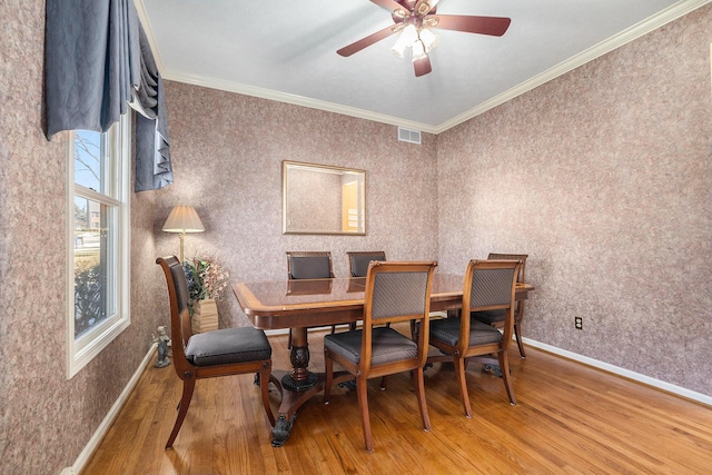 dining room with visible vents, crown molding, baseboards, and wood finished floors