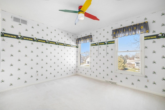 spare room with carpet floors, visible vents, ceiling fan, and wallpapered walls