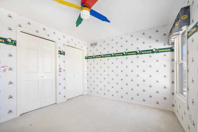 interior space with carpet floors, visible vents, baseboards, and wallpapered walls