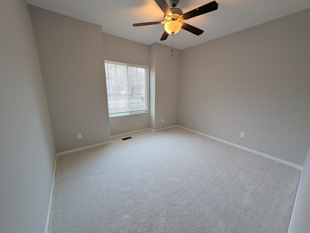 empty room featuring baseboards, visible vents, a ceiling fan, and light colored carpet