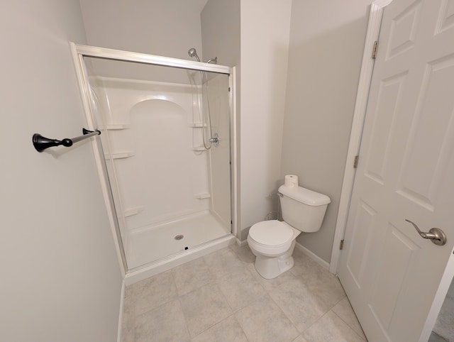 bathroom with a stall shower, baseboards, toilet, and tile patterned floors