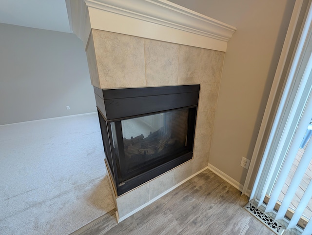 details featuring carpet flooring, a multi sided fireplace, baseboards, and wood finished floors