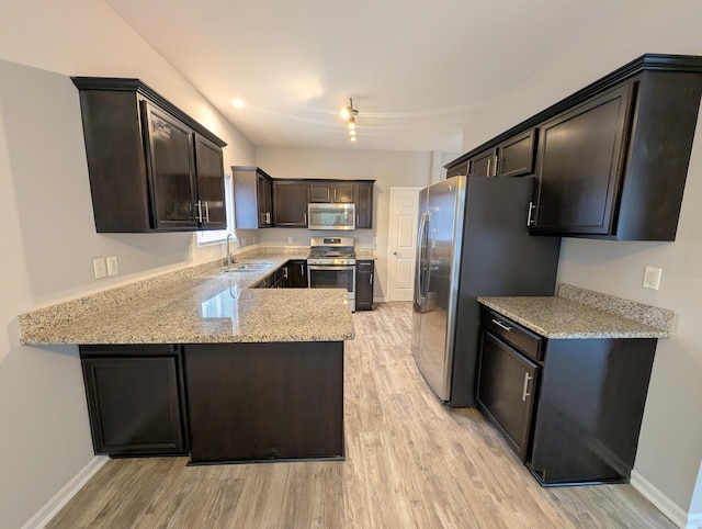 kitchen with light stone counters, a sink, baseboards, light wood-style floors, and appliances with stainless steel finishes