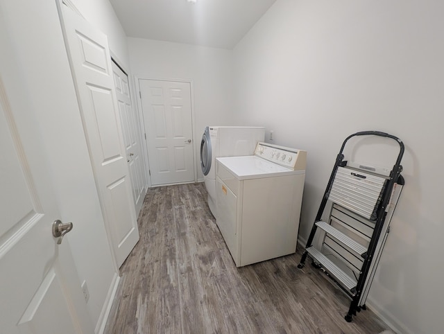 laundry area featuring washing machine and dryer, laundry area, baseboards, and wood finished floors