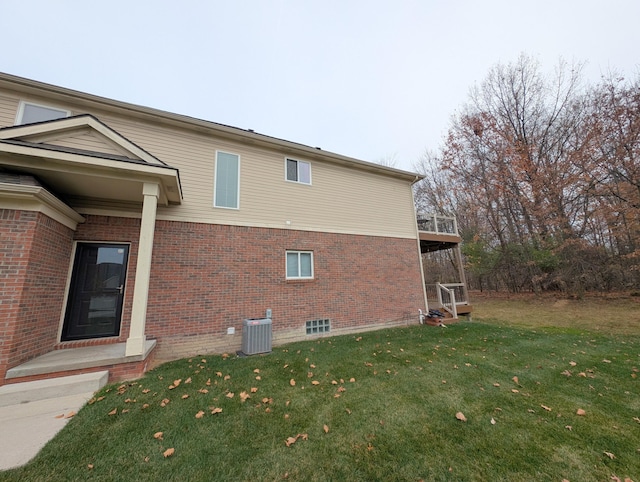 view of side of property with brick siding, a lawn, and central AC unit